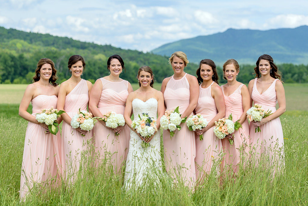 Bride and bridesmaids standing together at Vermont wedding venue with mountain views