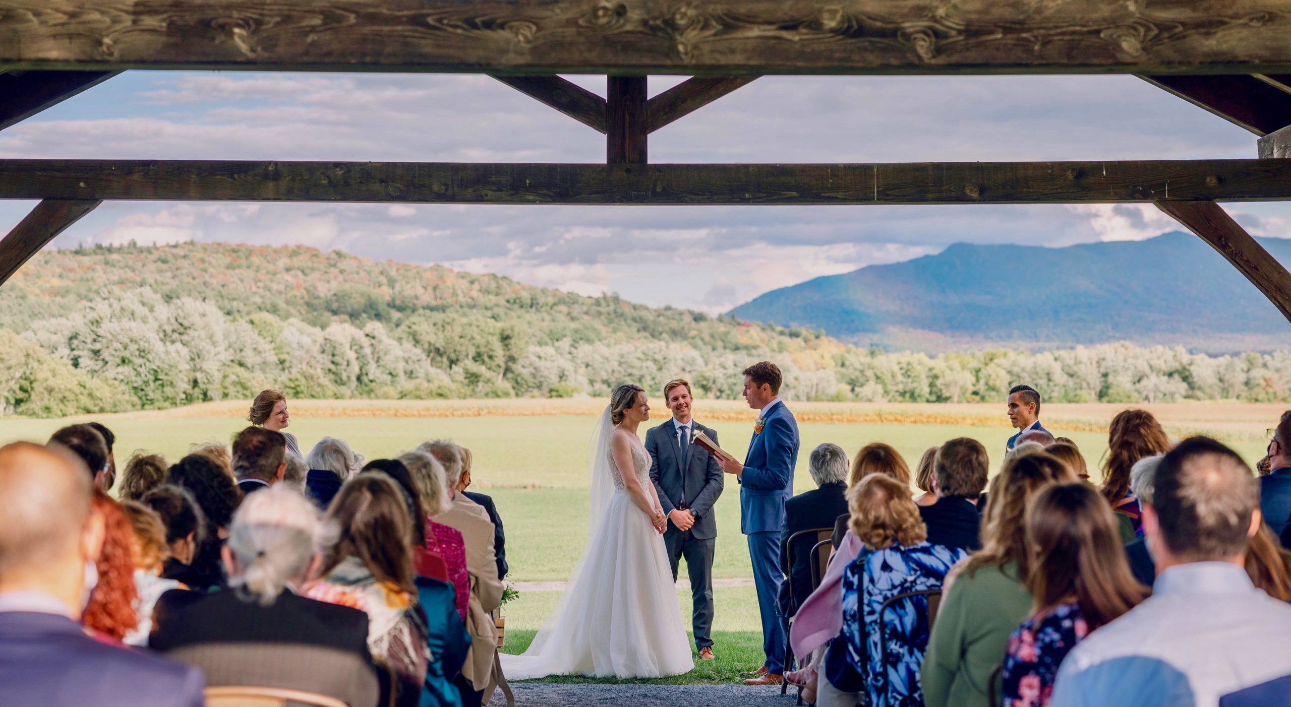 Couple standing at their outdoor wedding ceremony underneath a post and beam pavilion
